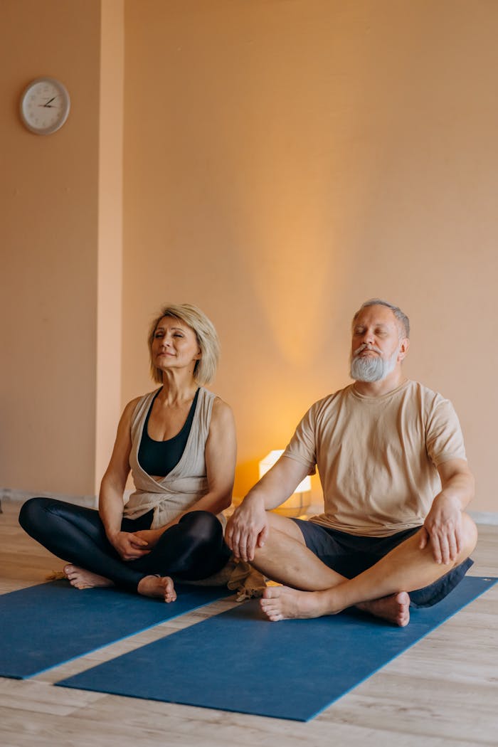 Senior couple meditating together indoors, promoting positive aging and wellness.