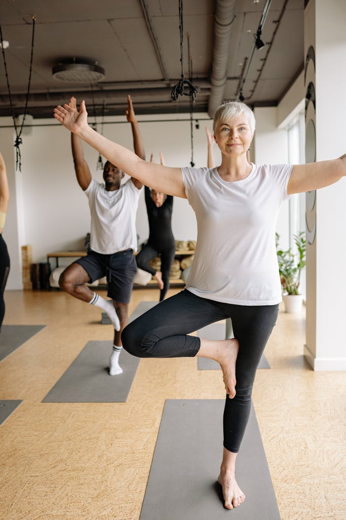 Elderly woman practicing yoga in a calm studio setting, focusing on balance and well-being.