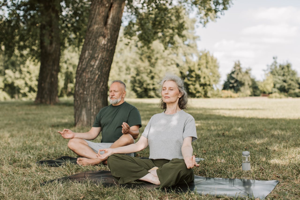 services-04 Senior couple meditating on yoga mats outdoors, embracing a healthy lifestyle.